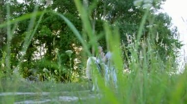 Anne ve kızı alanı yürüyor, kızı bir midilli sürme, anne midilli a at başlığı için bekletme. Neşeli, mutlu aile tatili. Forest yakınındaki yaz aylarında açık havada