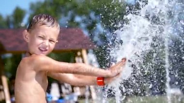 Mayo, yedi yaşında bir çocuk çeşme banyo, etrafında koşmak, ufaklık, iyi eğlenceler, sıcak yaz gününde. Ağır çekim.