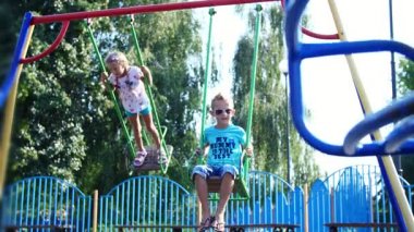 Mutlu çocuk, bir kız ve bir erkek yedi, sıcak bir yaz günü bir salıncağa binmek. Ağır çekim. Mutlu çocukluk, tatil.