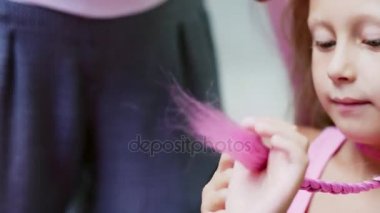 Güzel sarışın kız, yedi yaşında, iki kuyruklu örgülü, Güzellik Salonu, büyük bir ayna önünde bir kuaför salonu saç pembe kilitleri ile bir saç modeli yapmak. küçük bir prenses