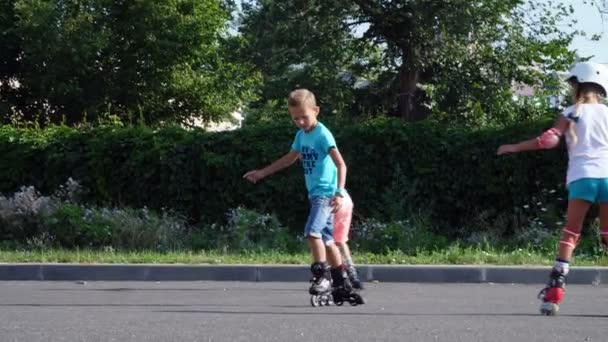 Niños felices, dos chicos de siete años, patinando, un caluroso día de verano. Movimiento lento — Vídeo de stock