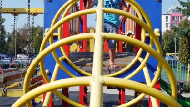Netter Junge von sieben Jahren, mit Sonnenbrille, der sich im Sommer auf einem Spielplatz im Freien amüsiert. Zeitlupe. Freude an aktiver Kindheit. — Stockvideo