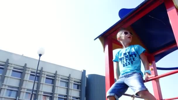 Lindo chico de siete años divirtiéndose en un parque infantil al aire libre en verano. En cámara lenta. Alegre infancia activa . — Vídeos de Stock