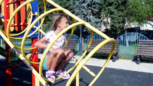 Chica feliz de siete años jugando en el patio de recreo, divirtiéndose en el caluroso día de verano. En cámara lenta. Alegre infancia activa . — Vídeos de Stock