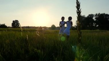 Siluetleri, çocuk, erkek ve kız atlama, eğleniyor, yaz aylarında gün batımında güneş, arka karşı dans figürleri. Mutlu bir aile. Ağır çekim