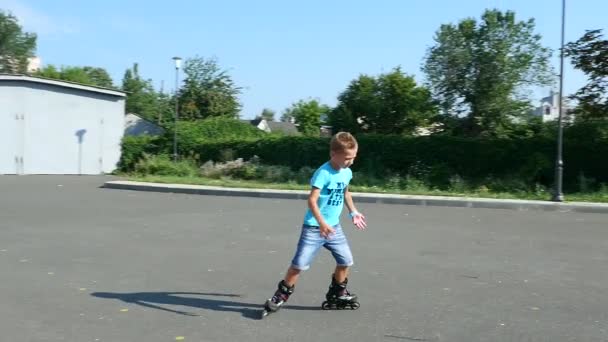 Ευτυχισμένο αγόρι των επτά, rollerblading, μια καυτή καλοκαιρινή μέρα. Αργή κίνηση — Αρχείο Βίντεο