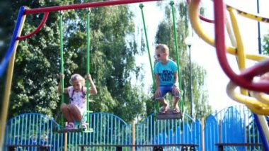 Mutlu çocuk, bir kız ve bir erkek yedi, sıcak bir yaz günü bir salıncağa binmek. Ağır çekim. Mutlu çocukluk, tatil.