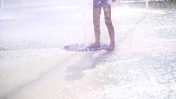 Chico emocionado de siete años divirtiéndose entre chorros de agua, en la fuente, correr, espolvorear, divertirse, divertirse, en un día caluroso de verano. Verano en la ciudad. Movimiento lento — Vídeo de stock