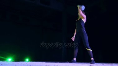 Ağırlıkları ile çeşitli güç egzersizleri yapıyor atletik, güzel genç bir kadın. Geceleri, projektörler, hangarda bir eski terk edilmiş, Bina hafif duman, sis ışığında