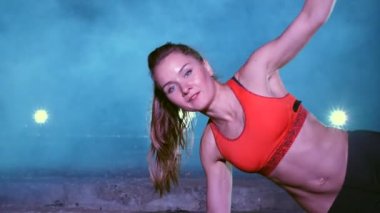 atletik, seksi bir kadın fitness trx sistemi, Trx askı kayışları ile çalışmaları gerçekleştirir. Gece, çok renkli projektörler, ışığında hafif duman, sis içinde binayı terk