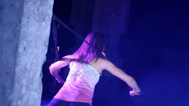 atletik, seksi bir kadın fitness trx sistemi, Trx askı kayışları ile çalışmaları gerçekleştirir. Gece, çok renkli projektörler, ışığında hafif duman, sis içinde binayı terk