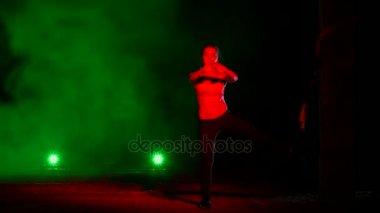 atletik, seksi bir kadın fitness trx sistemi, Trx askı kayışları ile çalışmaları gerçekleştirir. Gece, çok renkli projektörler, ışığında hafif duman, sis içinde binayı terk