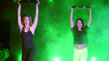 İki atletik, güzel, gece, terk edilmiş eski bir hangarda çok renkli projektörler ışığında hafif duman, sis ağır plakalı güç egzersizleri yapıyor kadın,