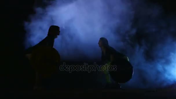 Dwa sportowe dziewcząt, sportowców, Robienie ćwiczeń ze sztangą. W nocy, w świetle reflektory, stobascope, w światło, dym, mgła, w starym, opuszczonym budynku. — Wideo stockowe
