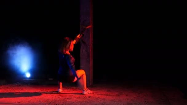 Athlétique, femme sexy effectue des exercices avec le système de fitness trx, sangles de suspension TRX. La nuit, dans la fumée légère, le brouillard, à la lumière de projecteurs multicolores, dans un bâtiment abandonné — Video