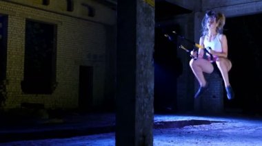 atletik, seksi bir kadın fitness trx sistemi, Trx askı kayışları ile çalışmaları gerçekleştirir. Gece, çok renkli projektörler, ışığında hafif duman, sis içinde binayı terk