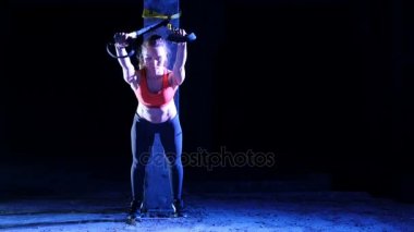 atletik, seksi bir kadın fitness trx sistemi, Trx askı kayışları ile çalışmaları gerçekleştirir. Gece, çok renkli projektörler, ışığında hafif duman, sis içinde binayı terk