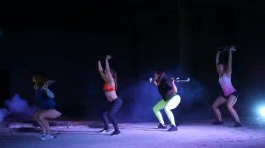 Fitness egzersizleri ile ağırlıkları, gece, terk edilmiş eski bir hangarda bir stobascope ışığında hafif duman, sis yapıyor, Bina dört atletik seksi kadın