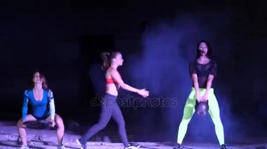 Fitness egzersizleri ile ağırlıkları, gece, terk edilmiş eski bir hangarda bir stobascope ışığında hafif duman, sis yapıyor, Bina dört atletik seksi kadın