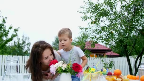 léto v zahradě. Maminka s čtyři rok starý syn udělat kytici květin. Chlapec to vzrušuje, baví, šňupání květiny. Rodina tráví společně svůj volný čas.