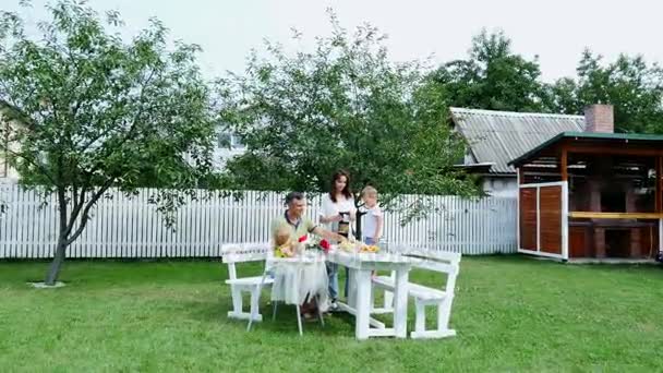 Happy rodinkou, maminku, tatínka, syna čtyři roky starý a jeden rok stará dcera, aby čerstvé ovocné šťávy. V létě se v zahradě. Rodina tráví společně svůj volný čas. — Stock video