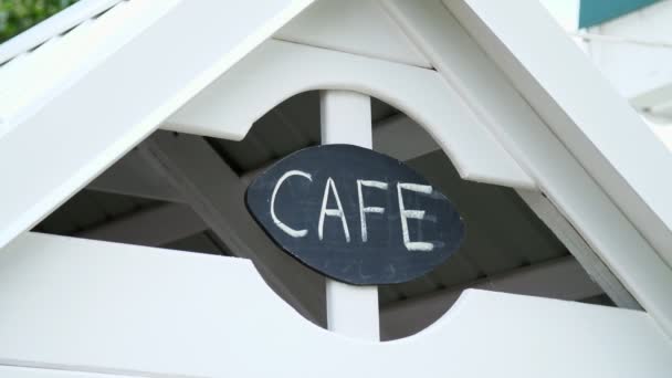 Ein Schild an einem Kinderspielhaus, die Inschrift eines Cafés, auf einer schwarzen Tafel in weißer Kreide Wort-Café geschrieben — Stockvideo