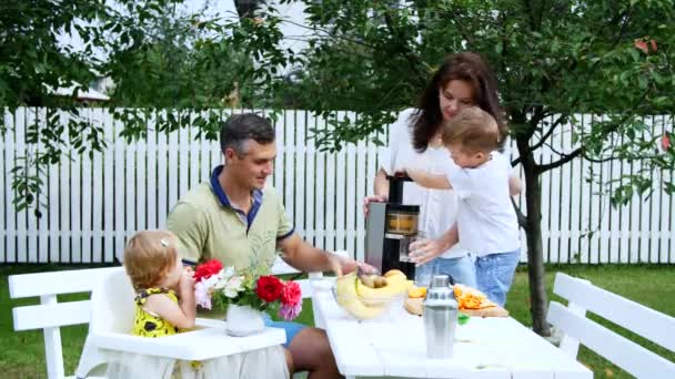 Happy rodinkou, maminku, tatínka, syna čtyři roky starý a jeden rok stará dcera, aby čerstvé ovocné šťávy. V létě se v zahradě. Rodina tráví společně svůj volný čas.