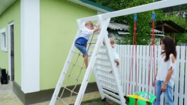 summer, bahçede, çocuk, dört yaşındaki bir çocuk ve bir yaşındaki kız tırmanmak çocuk merdivenlerden parkta. Aile birlikte onların boş zaman harcıyor.