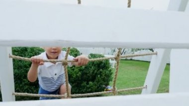 Yaz, Bahçe, çocuk, dört yaşında bir çocuk parkta çocuk merdivenlerden tırmanıyor. Aile birlikte onların boş zaman harcıyor.