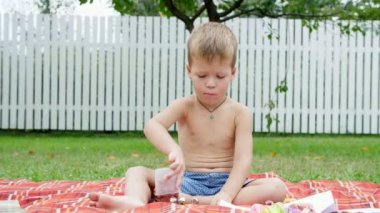 dört yaşındaki bir çocuk bahçesinde, yaz aylarında bir battaniye, yorgan, çim, çim, üzerinde oturan hamuru ile oynamak