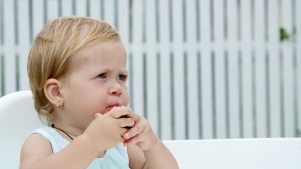 Verão, no jardim, engraçado menina loira de um ano de idade comendo melancia — Vídeo de Stock