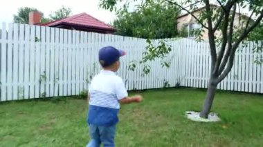 çıplak ayakla çimlerde, avlunun bir yeşil çim üzerinde yaz aylarında joggling dört yaşındaki çocuk. Güler, eğlenir