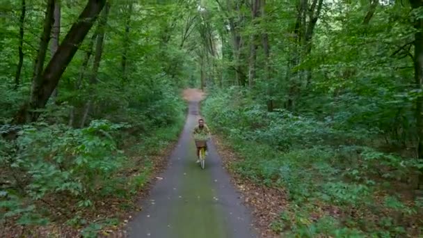 Un hombre con un niño en bicicleta en el bosque, en el verano, el niño está sentado en una silla especial — Vídeos de Stock