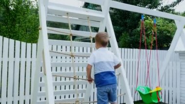 Yaz, Bahçe, çocuk, dört yaşında bir çocuk parkta çocuk merdivenlerden tırmanıyor. Aile birlikte onların boş zaman harcıyor.