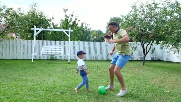 Táta s čtyři rok starý syn hrát míč, fotbal, na dvoře na zeleném trávníku, v létě. — Stock video