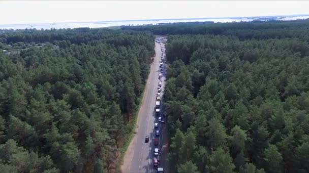 Aero video-opname. Dag, zomer, landschap, midden in het bos is er een weg. Onderweg zijn er een heleboel auto's, in lijn, files. — Stockvideo