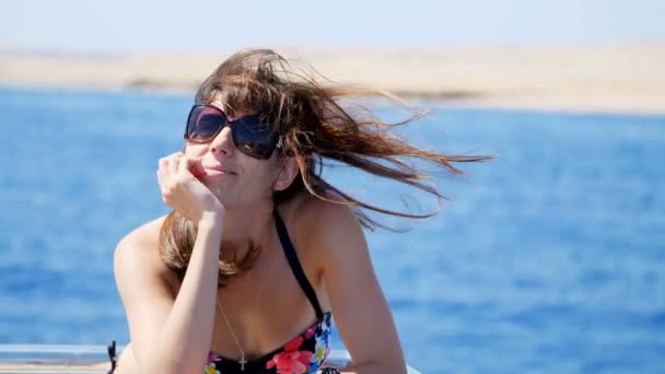 Verano, mar, retrato, hermosa joven morena vistiendo un traje de baño y gafas de sol, de pie en la cubierta, disfrutando del resto, su pelo revoloteando en el viento, feliz , — Vídeo de stock