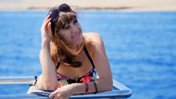 Verano, mar, retrato, hermosa joven morena vistiendo un traje de baño y gafas de sol, de pie en la cubierta, disfrutando del resto, su pelo revoloteando en el viento, feliz , — Vídeo de stock