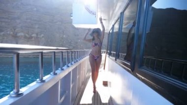 Yaz, deniz, bir feribot tekne, gemi, güneş ışığı altında güverte boyunca yürüyüş mayo, güneş şapka ve güneş gözlüğü, giyen güzel seksi genç esmer kadın