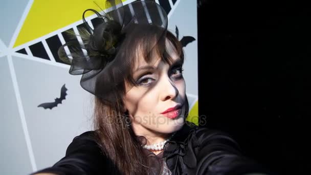 Хеллоуїн вечірка, ніч, лякаючий портрет жінки з жахливим макіяжем в чорному костюмі відьми, шахраї перед камерою — стокове відео