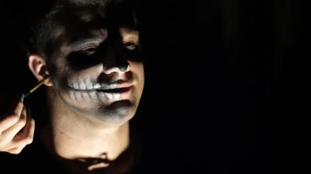 Fiesta de Halloween, primer plano, maquillador dibuja un maquillaje terrible en la cara de un hombre para una fiesta de Halloween . — Vídeos de Stock
