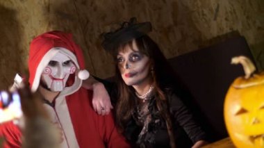 Cadılar Bayramı partisi, gece, ışık, kötü bir Noel Baba ve korkunç bir makyaj bir kadınla randevuda Cadılar Bayramı yaşıyorsanız gibi giyinmiş bir adam ışınları alacakaranlıkta tarzı tarihi