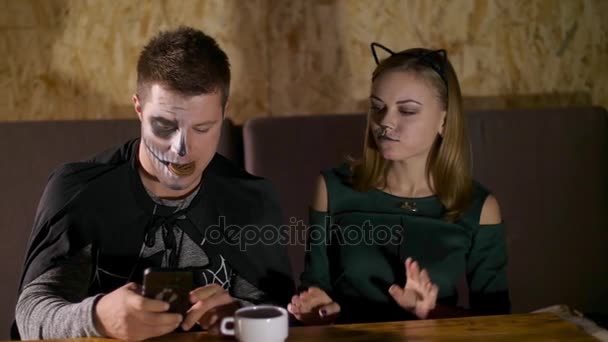 Ett datum i stil med Halloween-fest, en kille med en flicka klädd i kostymer och med en fruktansvärd makeup gör selfie, de kraxande framför kameran, titta in i telefonen — Stockvideo