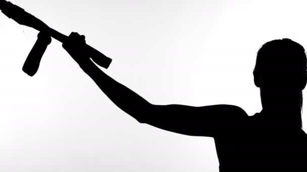 Sur fond blanc, une ombre, un contour noir d'une silhouette féminine faisant des exercices avec système trx fitness, sangles de suspension TRX . — Video