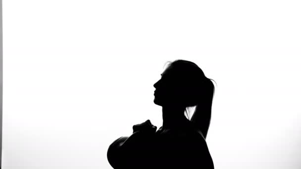 Na bílém pozadí stín, černý obrys ženské postavy dělá cvičení dělá cvičení s váhou, použitím váhy — Stock video