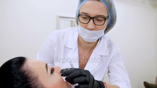 Sala de cosmetología en la clínica, una doctora en forma blanca, inyectando ácido hialurónico en los labios de los pacientes. Procedimiento para aumentar el volumen de los labios, corrección de la forma de los labios . — Vídeo de stock