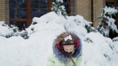 kış manzara çerçevede, kız kar ile bahçede eğlenceli çalış, atar, kar kürekle sprinkles. Eğleniyor shes.