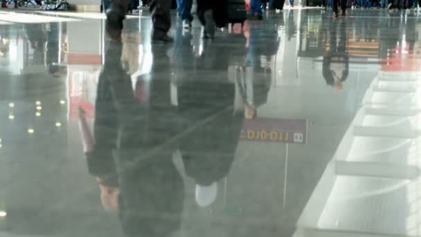 Flughafen, Warteraum, auf dem Fliesenboden spiegeln sich Figuren von Menschen. Menschen eilen hin und her. — Stockvideo
