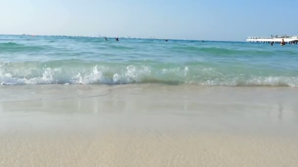 Dubai, Verenigde Arabische Emiraten, Verenigde Arabische Emiraten - 20 November 2017: Hotel Jumeirah Al Qasr Madinat, beach, surf, in water mensen zwemmen, rust. in de verte ziet u zeilregatta. — Stockvideo