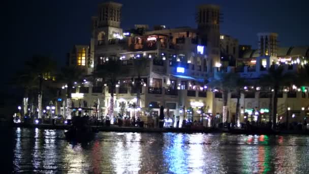 DUBAI, EMIRATOS ÁRABES UNIDOS, Emiratos Árabes Unidos - 20 de noviembre de 2017: Hotel Jumeirah Al Qasr Madinat, paseo nocturno por el canal de agua, en barco. Las linternas iluminan los edificios — Vídeo de stock